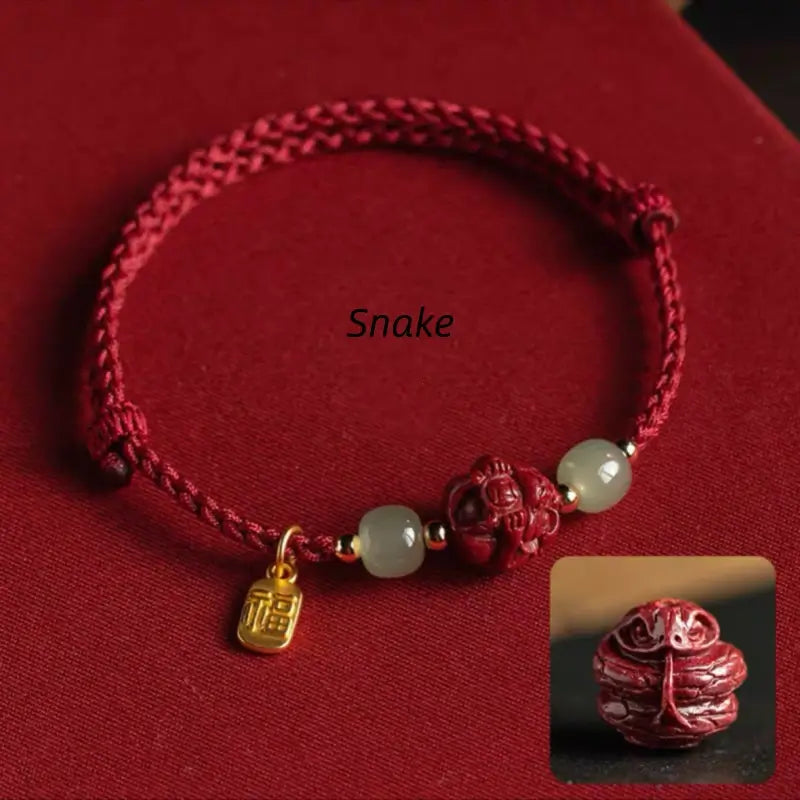 Red string lucky bracelet featuring carved Snake zodiac cinnabar bead and gold Fu pendant charm.