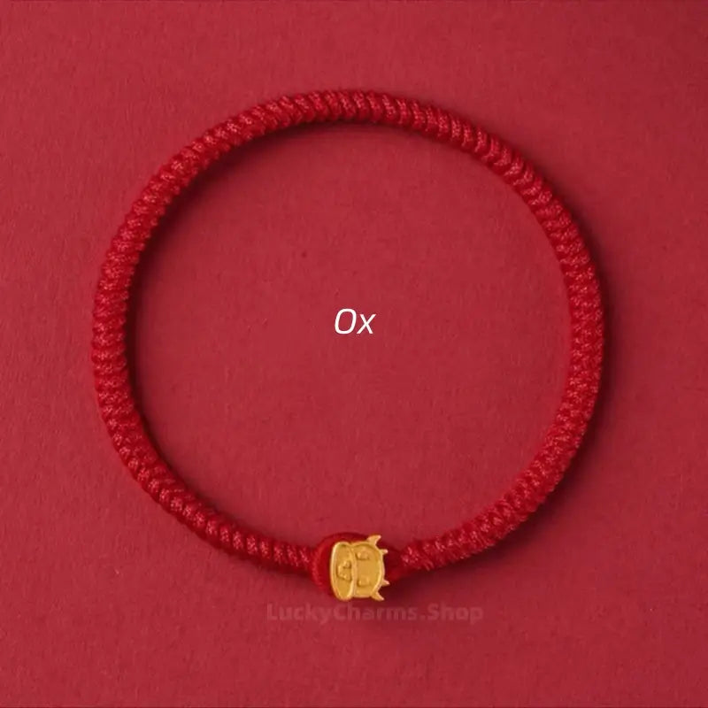 Red braided cord protection bracelet accented with a gold Ox Chinese zodiac clasp against a red background.