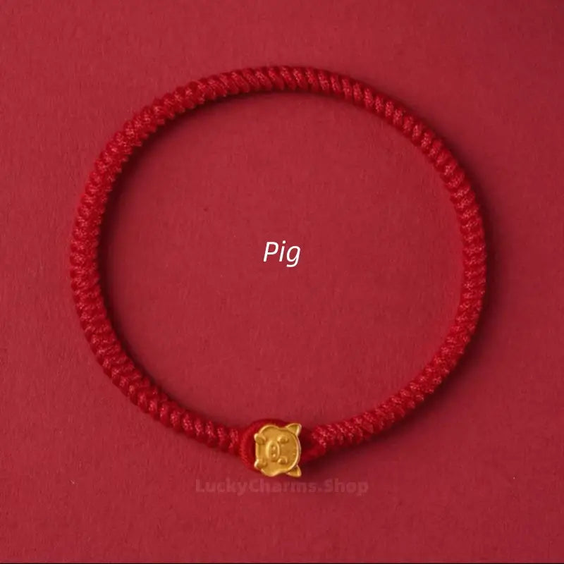 Handwoven red string luck bracelet with a cute gold Pig Chinese zodiac charm clasp on a red background.