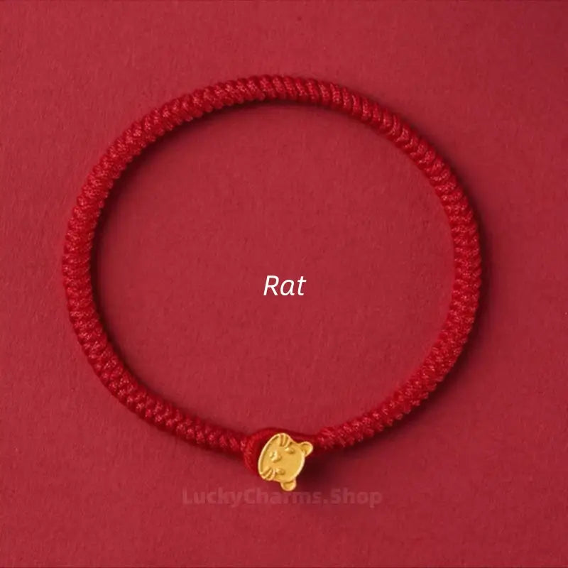 Braided red string protection bracelet featuring a small gold Rat Chinese zodiac clasp on a red background.