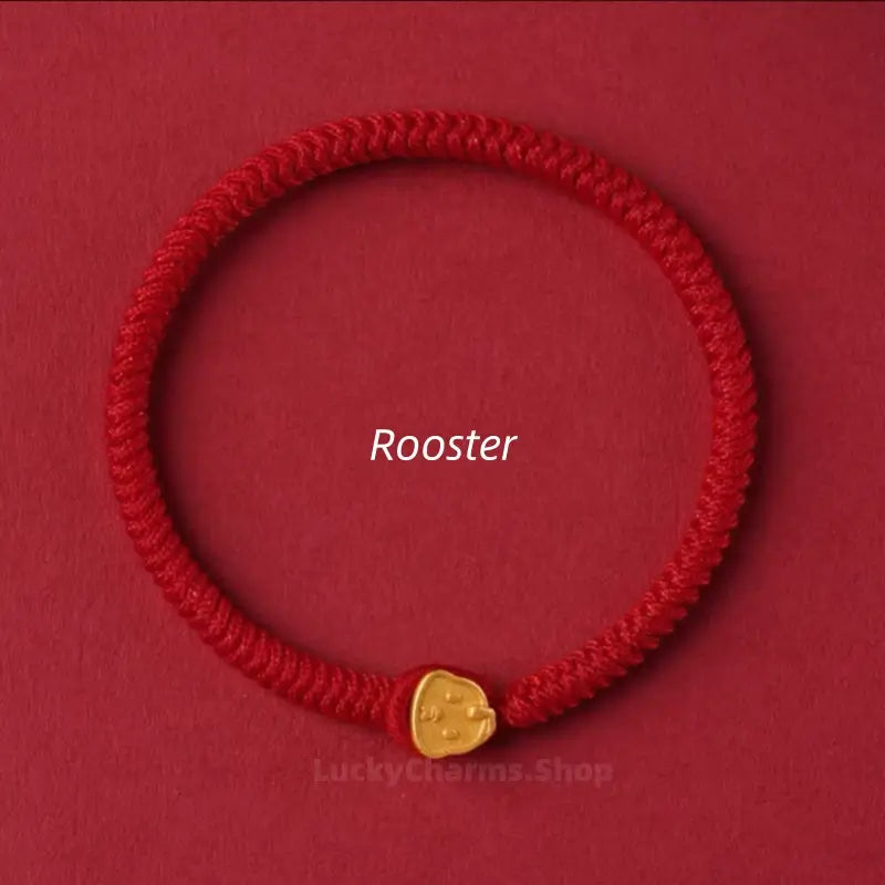 Red woven cord bracelet designed with a gold Rooster Chinese zodiac animal clasp against a red surface.