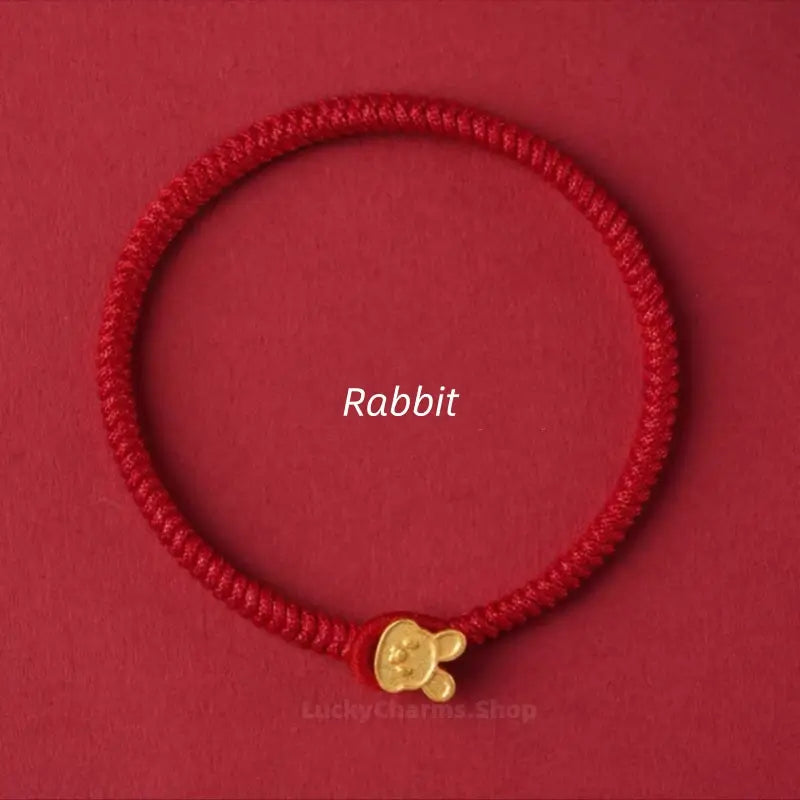 Handwoven red string lucky bracelet featuring a cute gold Rabbit Chinese zodiac clasp on a red background.