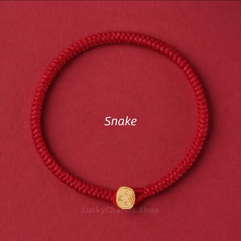 Red braided string protection bracelet showcasing a gold Snake Chinese zodiac charm clasp on red surface.