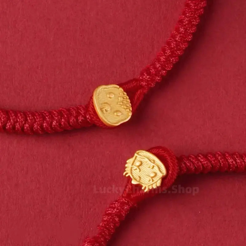 Close-up view of handwoven red cord bracelets showcasing intricate gold Chinese zodiac animal-shaped clasps.