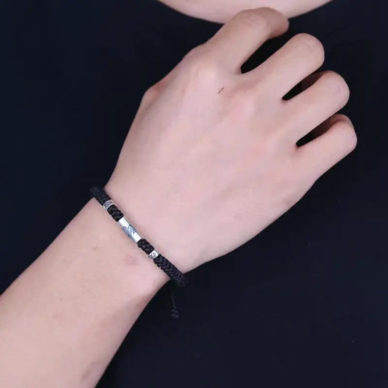 Man wearing a braided black rope bracelet featuring a 925 sterling silver LuLuTong mantra bead.
