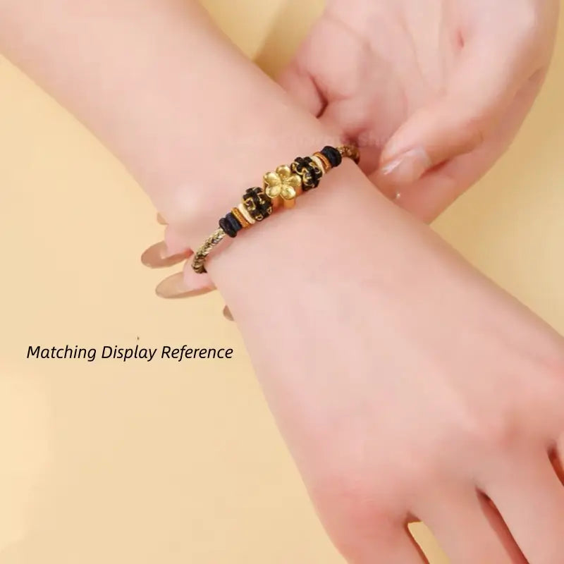 On-wrist model displaying a braided rope bracelet styled with a gold flower charm bead.