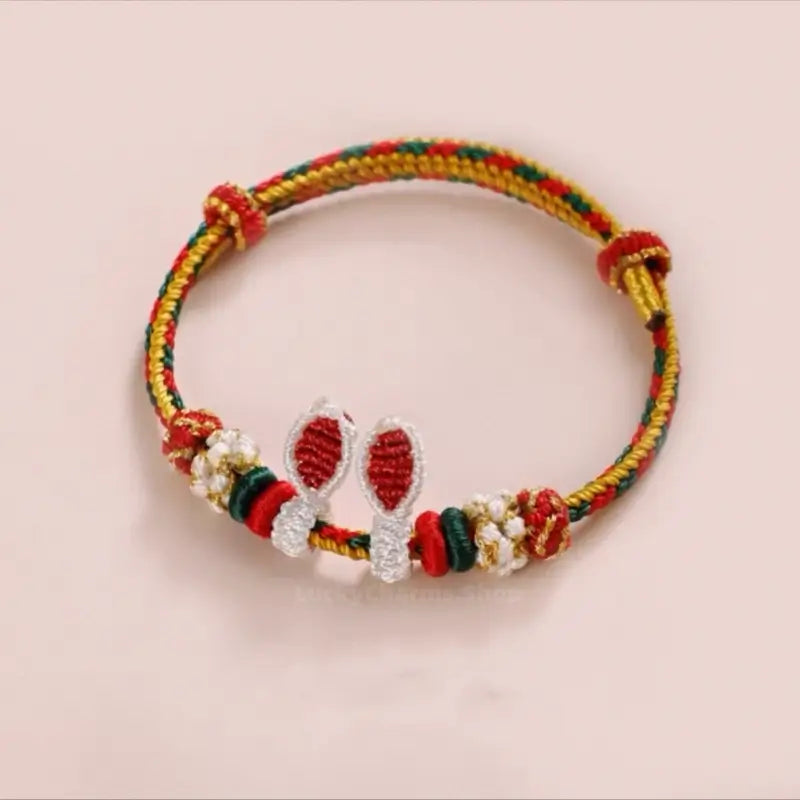 Colorful red, green, and gold braided rabbit ear bracelet with adjustable sliding knots.