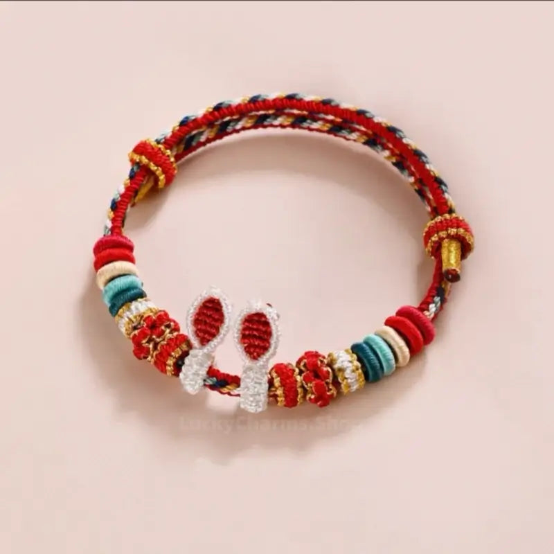 Red and multi-color braided lucky rabbit ear hand rope bracelet with sliding knots.