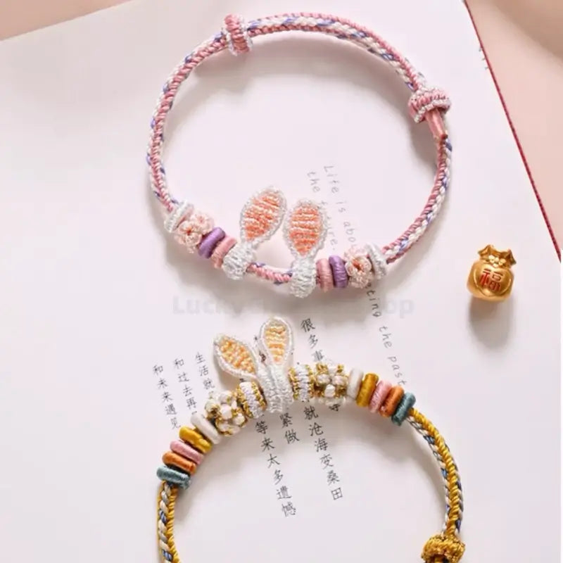 Pink and yellow handmade braided rabbit ear rope bracelets with spacer beads.