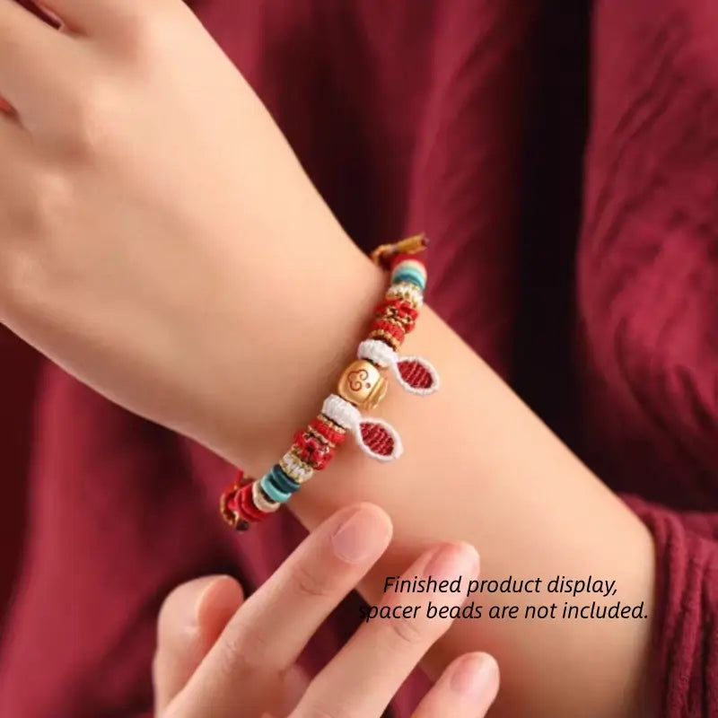 On-wrist view of red handmade braided rabbit ear bracelet with gold lucky charm.
