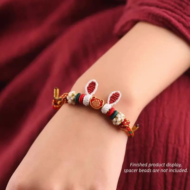 On-wrist view of red braided rabbit ear bracelet featuring central gold Fu charm.