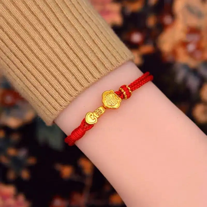Woman wearing a red braided string bracelet with a gold-plated Fu lock clasp on her wrist.