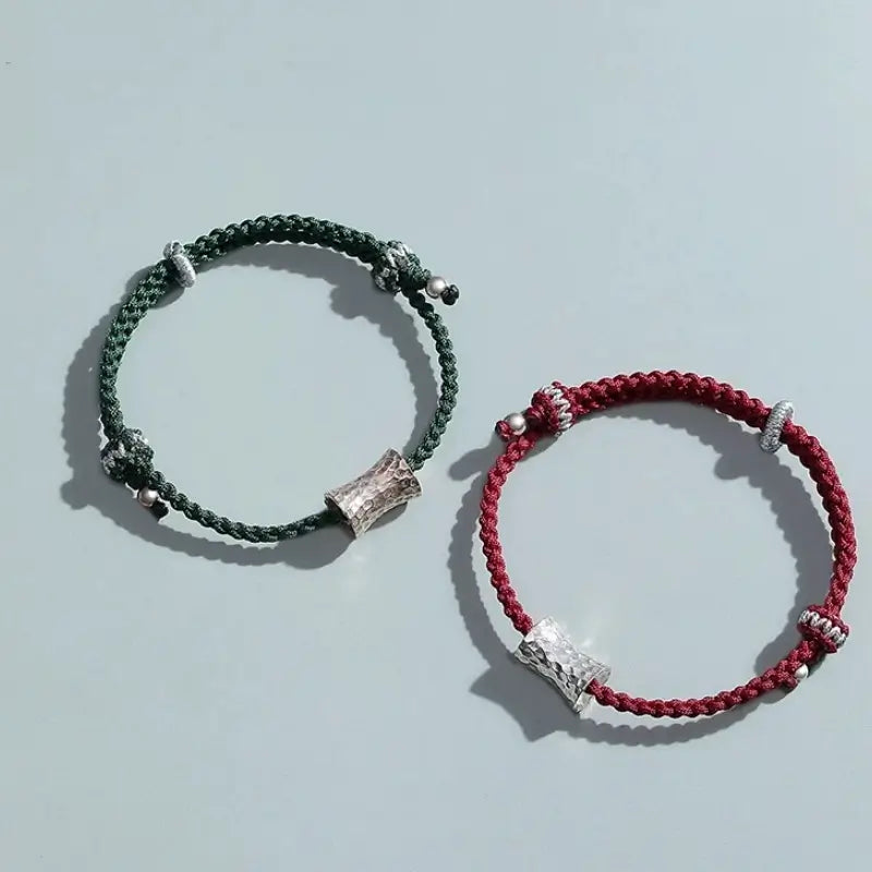 op view of dark green and red braided string couple bracelets featuring textured silver Lu Lu Tong beads.