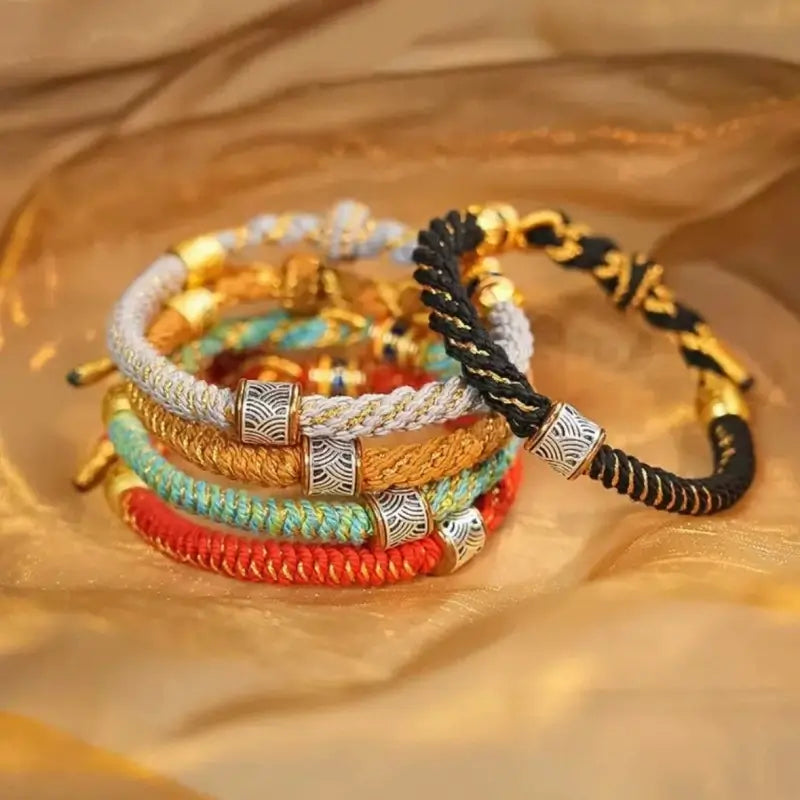 Stack of colorful woven Five Elements guardian bracelets featuring engraved silver wave pattern charm beads.