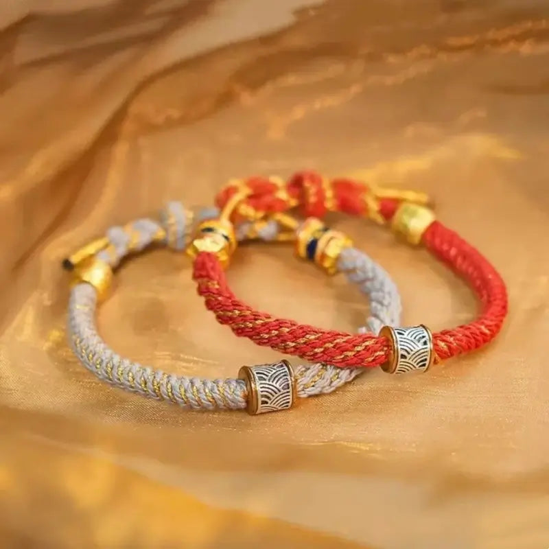 Handwoven red and light gray Five Elements lucky bracelets with gold-thread accents and silver beads.