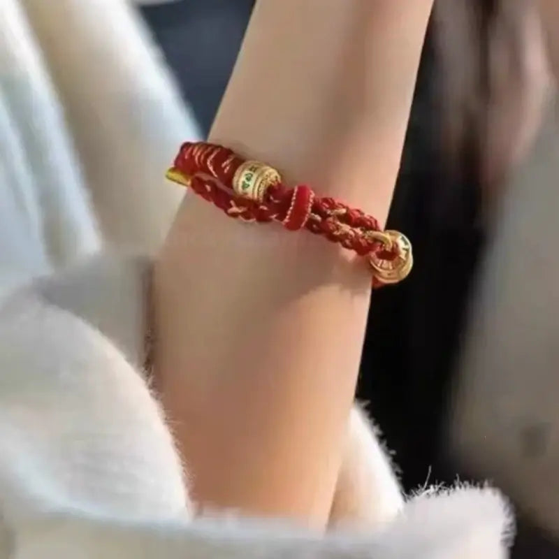 Woman wearing a red handwoven Five Elements guardian bracelet with gold mantra beads on her wrist.