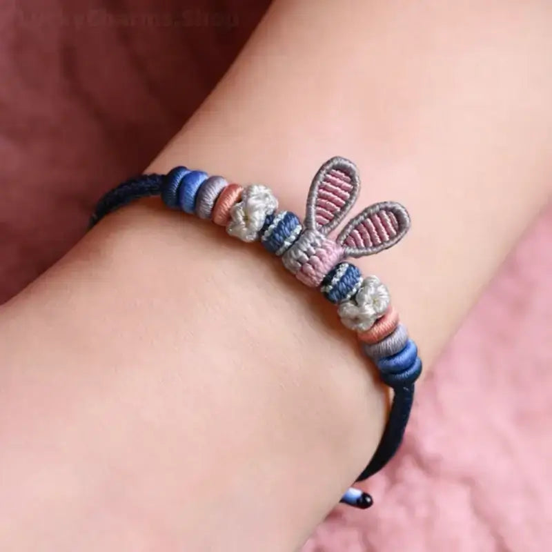On-wrist view of handmade braided blue Judy rabbit ears rope bracelet with adjustable knot.