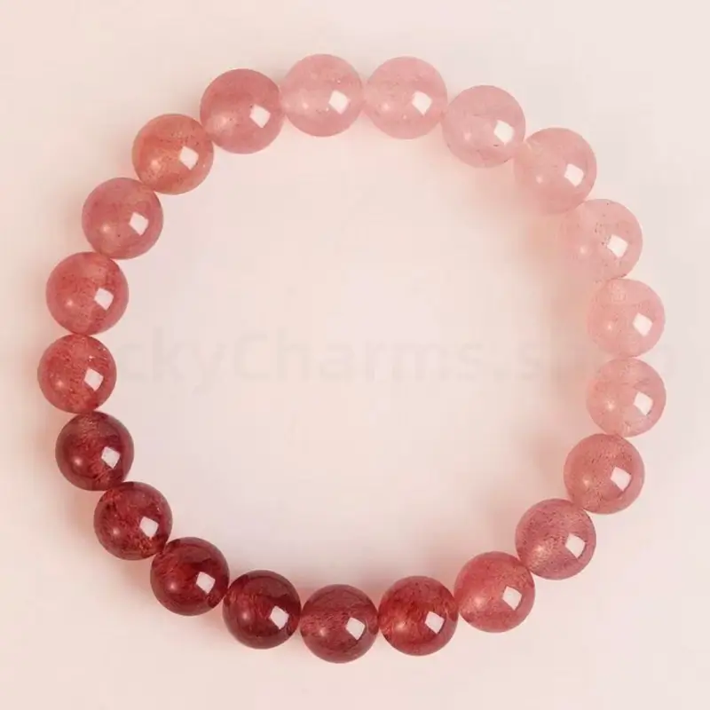 A top-down shot of an 8mm natural strawberry quartz bracelet showing a smooth color gradient from deep crimson red to soft pastel pink.