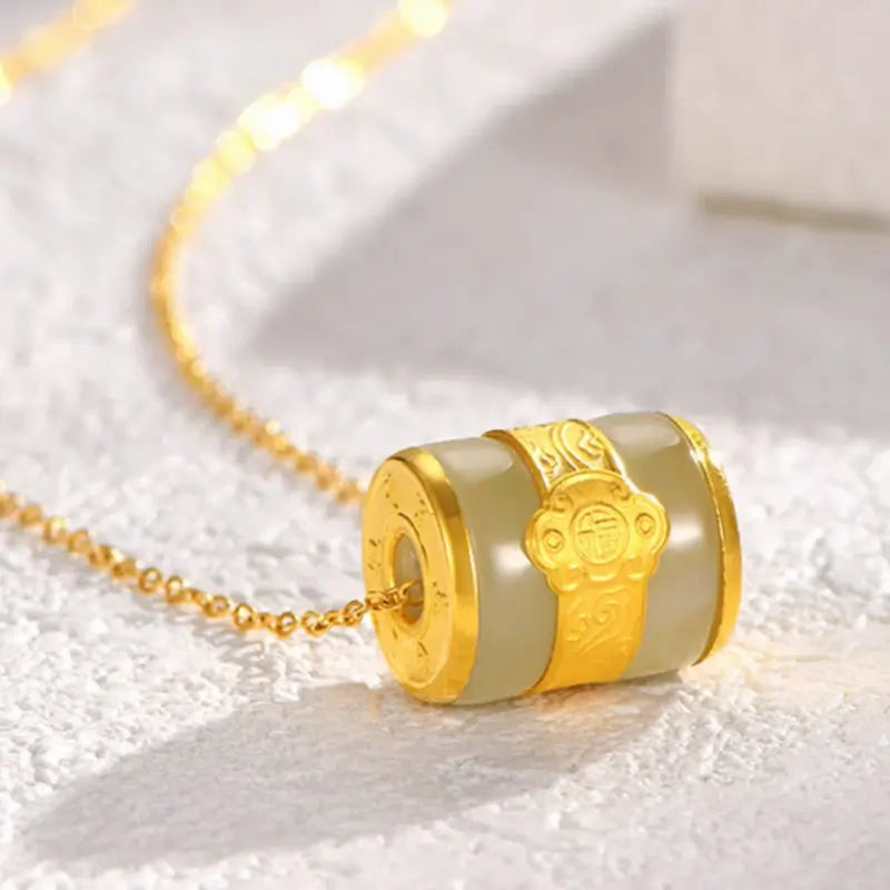 Close-up of gold-inlaid Hetian jade cylinder pendant featuring Chinese Fu character detail.