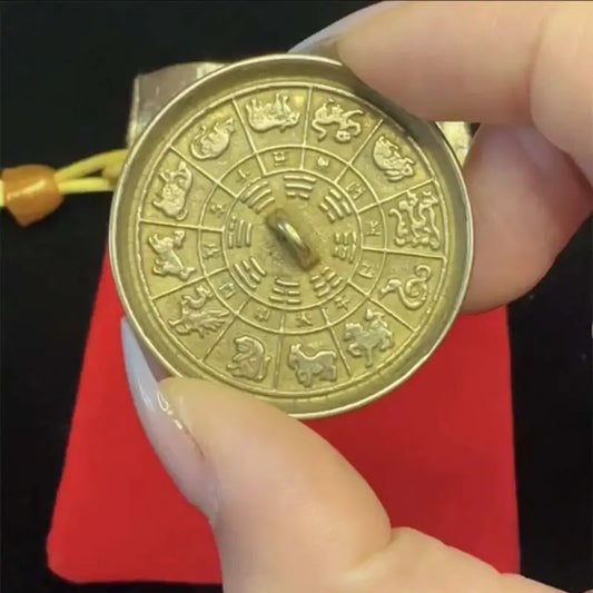 Hand holding brass magic mirror showing detailed 12 Chinese zodiac animals and Bagua carving.