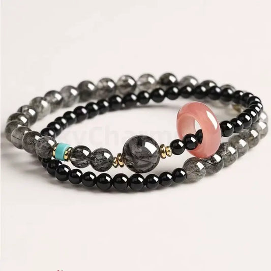 Double-layer black crystal energy bracelet showcasing a large rutilated quartz bead, gold accents, and a bright turquoise spacer