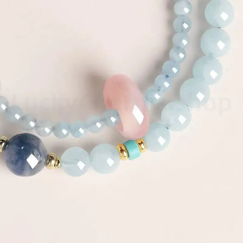 Faceted light blue aquamarine gemstone beads close-up detail with gold spacers and a small turquoise accent gem