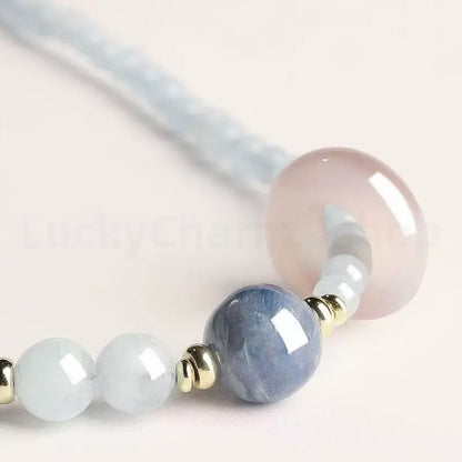 Macro shot of a blue kyanite crystal main bead and a smooth translucent pink quartz charm on a healing gemstone bracelet