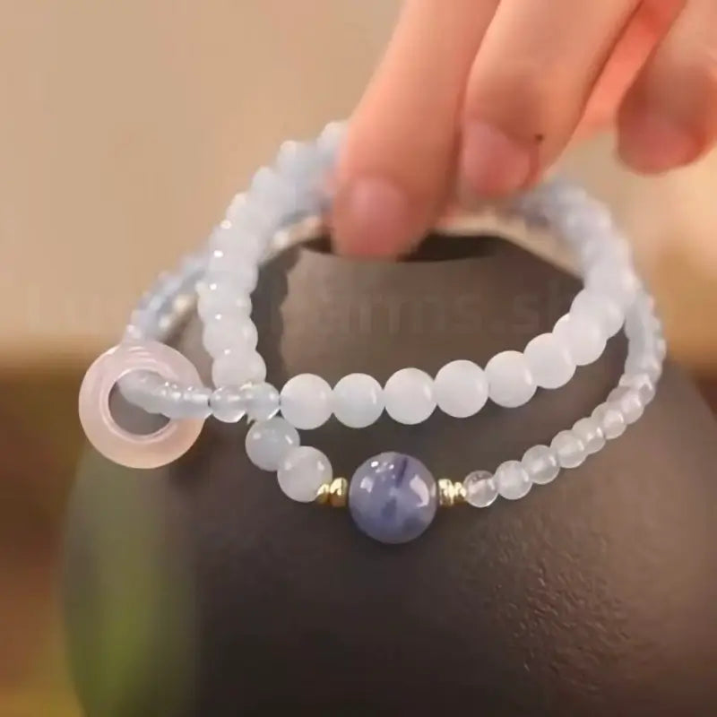 Light blue aquamarine and rose quartz double-layer energy bracelet displayed on a dark ceramic vase for home decor lifestyle