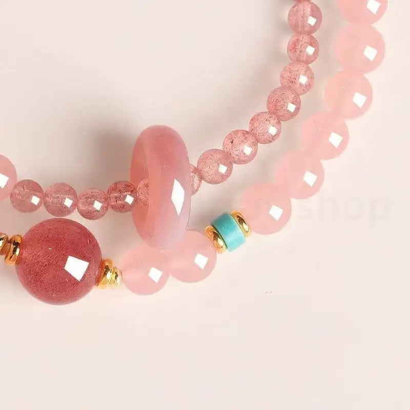 Macro shot of faceted strawberry quartz gemstone beads showing natural inclusions next to a bright turquoise spacer