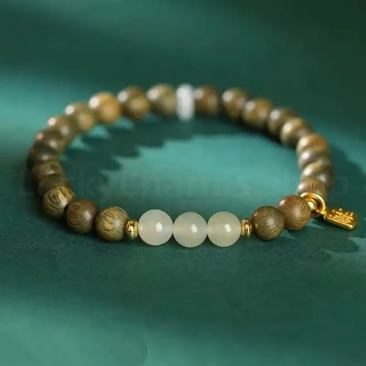 Elegant lifestyle shot of a woman wearing a single-strand 6mm green sandalwood beaded bracelet with a gold-plated charm for wealth and good luck.