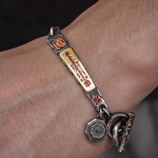 A man's wrist wearing the vintage Tibetan silver fortune bracelet with a gold-plated wealth-attracting talisman charm.