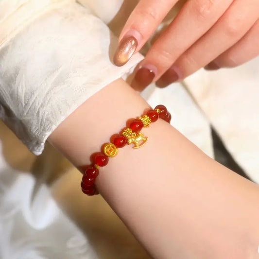 Elegant lifestyle shot of a woman wearing the 6mm red agate gemstone bracelet, showcasing the shiny gold-plated prosperity coin.
