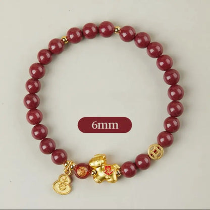 A delicate 6mm natural cinnabar beaded bracelet with gold-plated sterling silver horse, coin, and Wu Lou gourd charms.