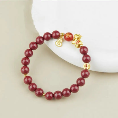 Natural cinnabar bead bracelet displayed on a white plate with a 925 silver gold-plated horse and lucky gourd charm.