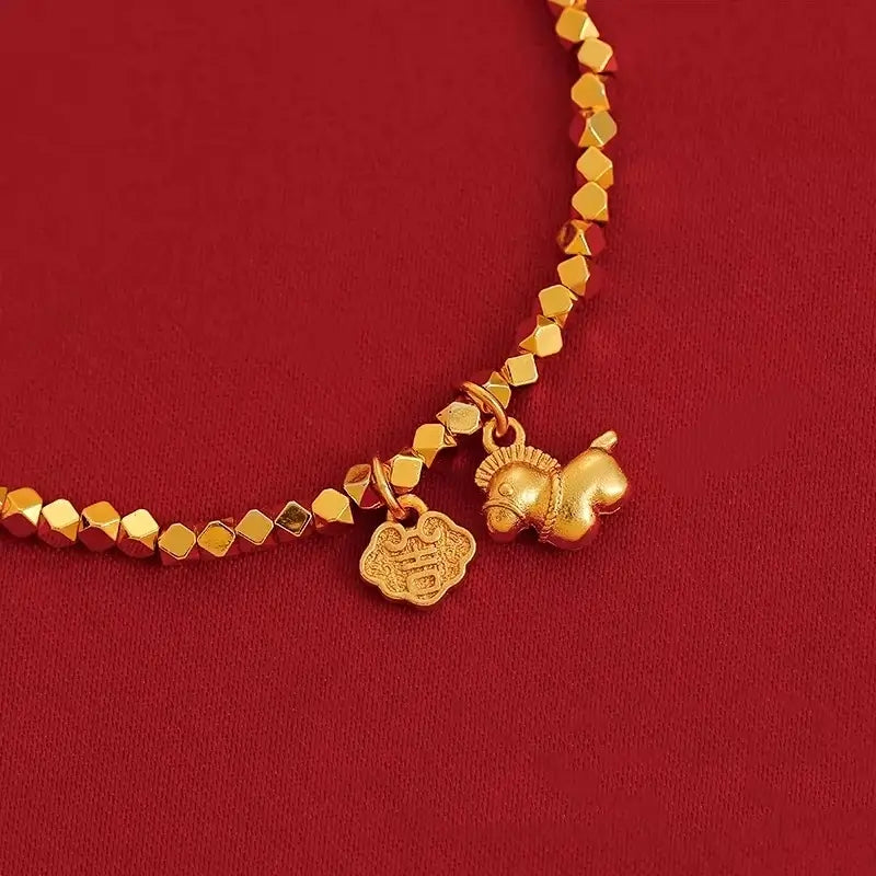 Macro detail shot of the gold-plated Ruyi lock charm engraved with the Chinese character for good luck, paired with a cute horse pendant.