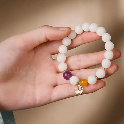 A woman holding the 8mm white jade bodhi seed bracelet with a purple amethyst accent in her palm, showcasing its smooth texture.