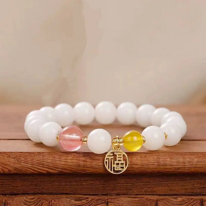 A luck-blessing bracelet made of 8mm white jade bodhi seeds, accented with a translucent pink strawberry quartz bead and a gold fortune amulet.