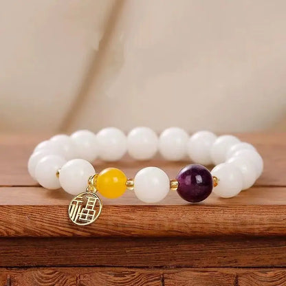 An 8mm white jade bodhi seed prayer bracelet featuring a rich purple amethyst bead and a gold hollow-out Fu blessing pendant on a wooden base.
