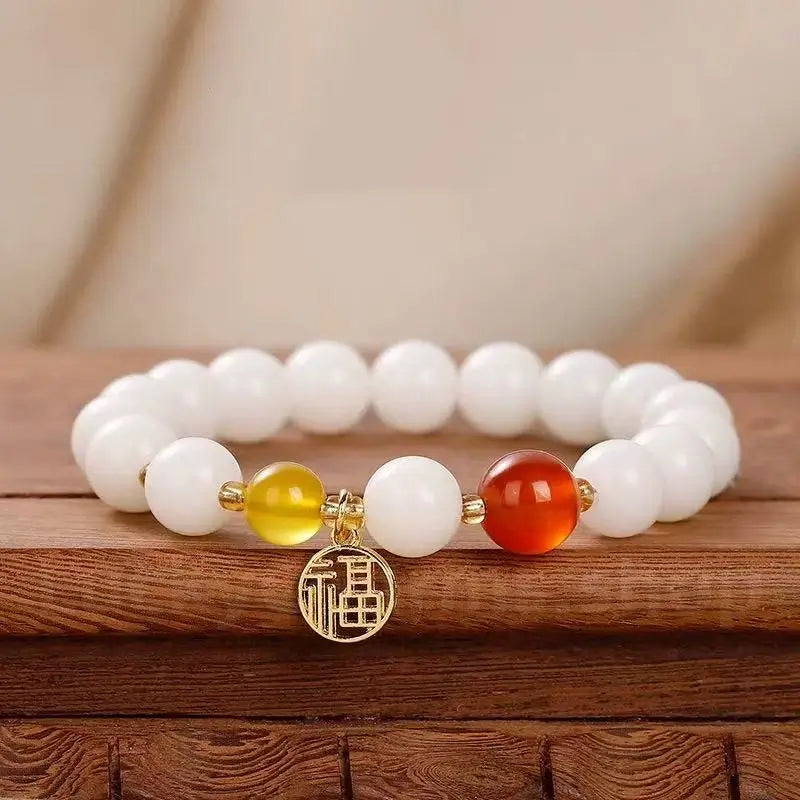 A traditional Chinese style 8mm white jade bodhi bead bracelet with a fiery red carnelian stone and a gold-plated good luck Fu charm.