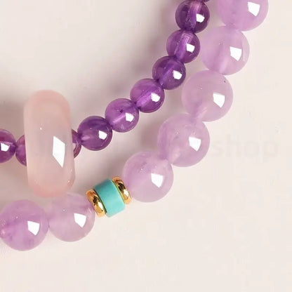 Macro shot of a double-layer lavender crystal bracelet featuring translucent purple beads and a smooth pink quartz charm