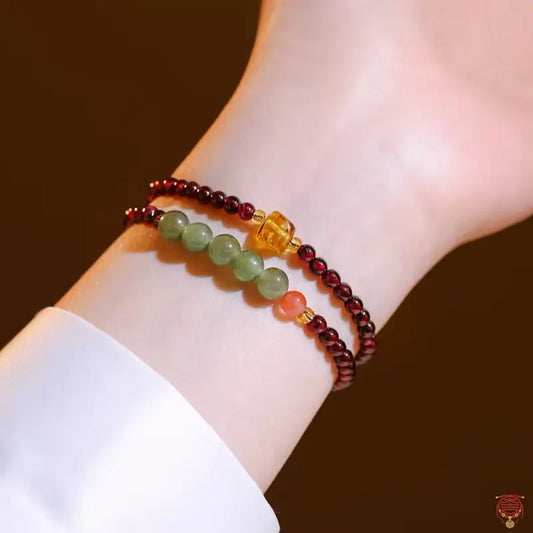 Close-up on wrist showing double-loop red garnet gemstone bracelet with green chalcedony beads.