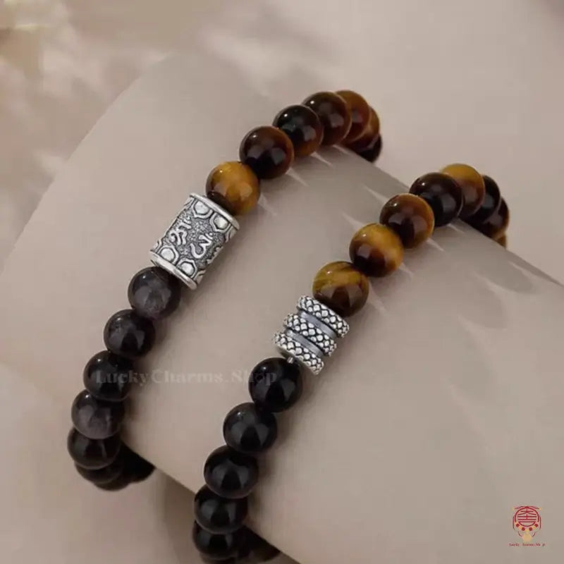 Side view of two natural gemstone mindfulness bracelets displaying polished chatoyant beads and silver spacers.