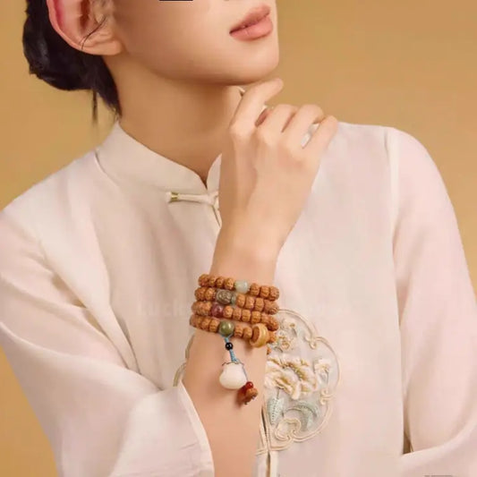 A lifestyle model shot of a woman in a traditional white linen dress wearing the Indonesian Rudraksha 108 mala bracelet, showcasing a timeless Zen fashion style.