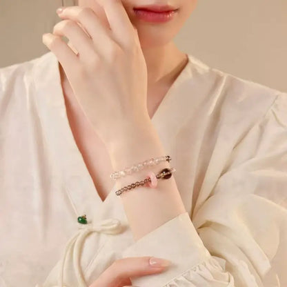 An elegant woman wearing the natural smoky quartz and pink crystal double-layer protection bracelet on her wrist