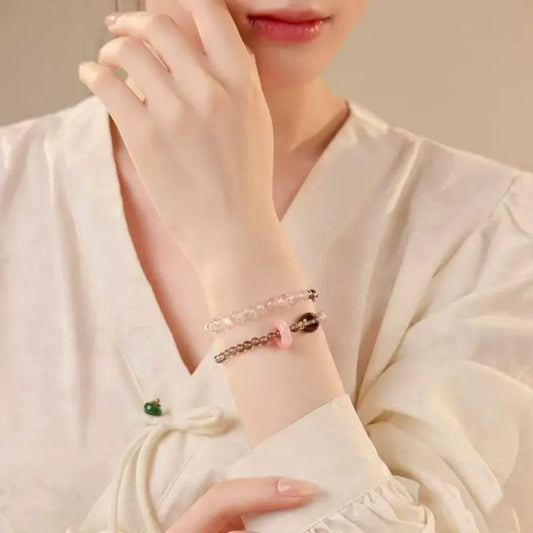 An elegant woman wearing the natural smoky quartz and pink crystal double-layer protection bracelet on her wrist