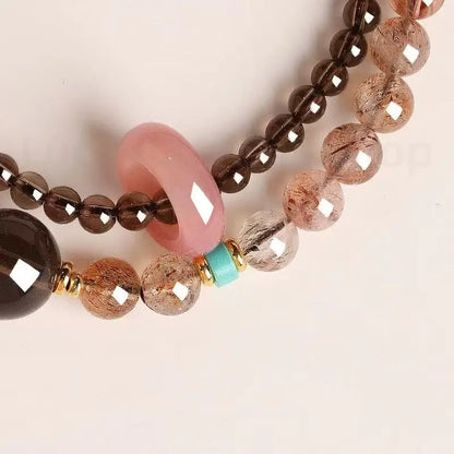 Macro shot of rutilated quartz beads showing internal needles next to a pink quartz donut and turquoise spacer
