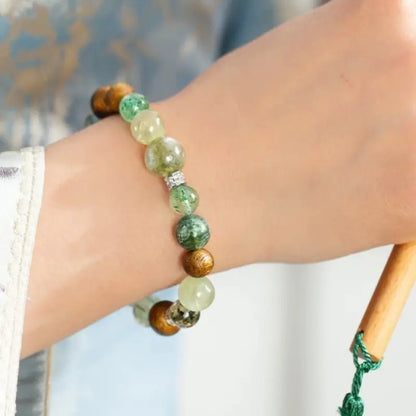 Wood element single-strand bracelet on wrist with green phantom, strawberry quartz, and agarwood beads.