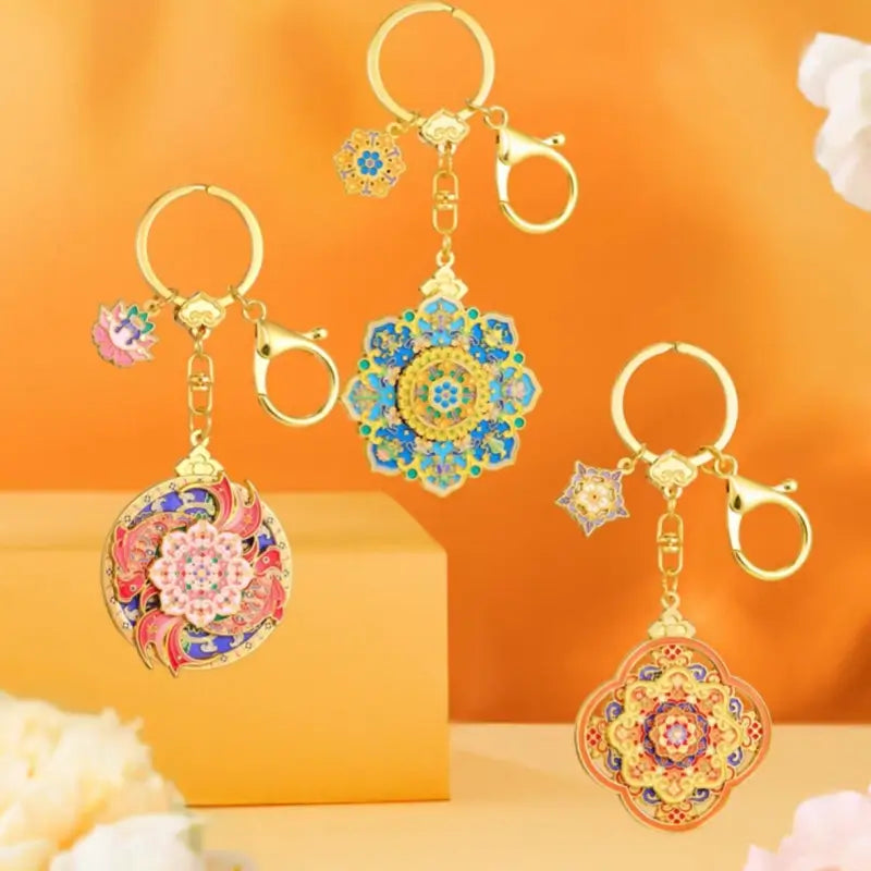 Three Prince Gong Mansion lucky rotating keychains displayed in blue, red, and orange enamel styles.