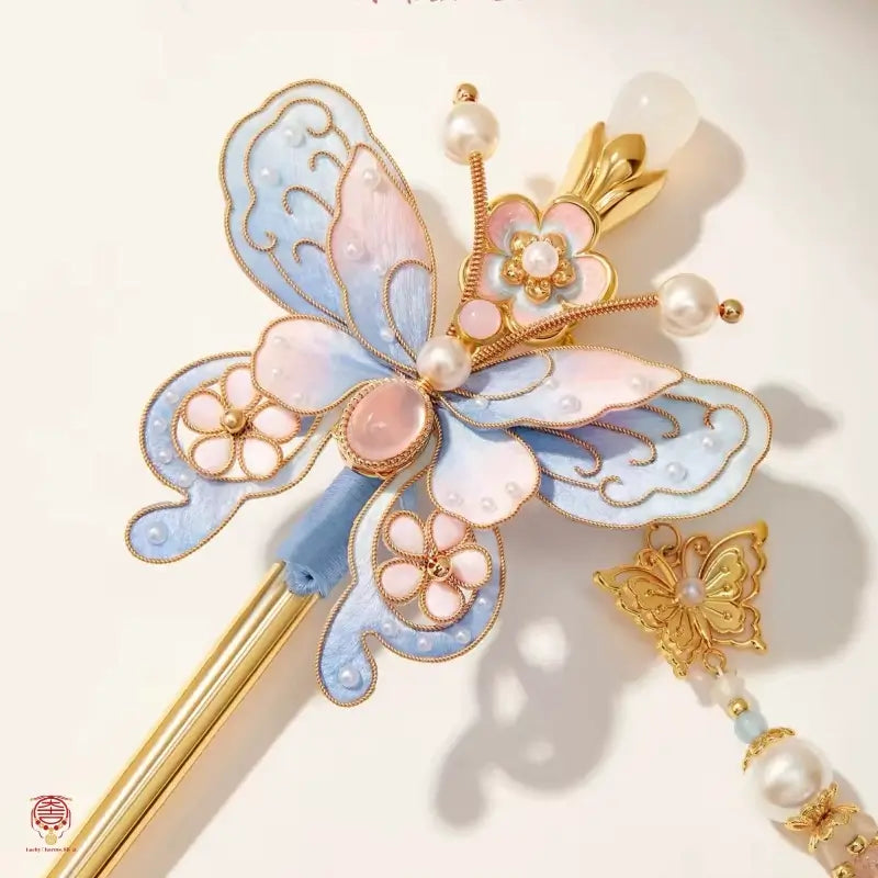 Macro detail of a blue velvet butterfly hair stick showing fine wire filigree and freshwater pearl embellishments.