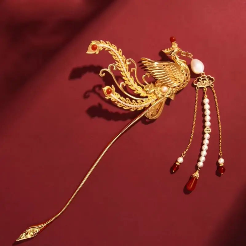 Palace Museum gold phoenix hairpin with pearls, red agate beads, and tassel chains on red background.